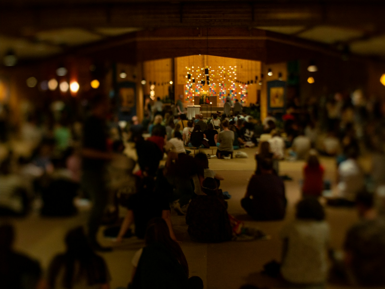 People meditate together inside a dimly lit hall.