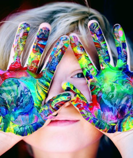 Vibrant close-up of a child's hands covered in colorful paint, expressing creativity and fun.