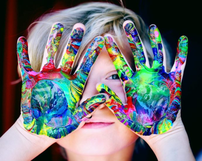 Vibrant close-up of a child's hands covered in colorful paint, expressing creativity and fun.