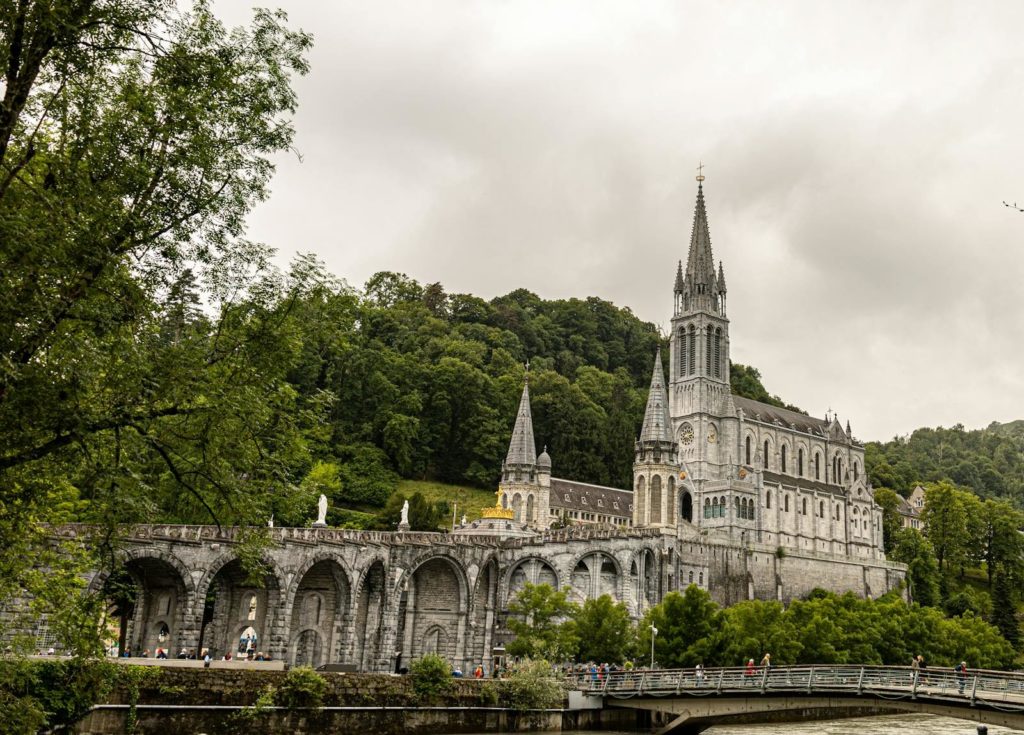 Stunning view of the Basilica of Our Lady of Lourdes against lush green landscape.