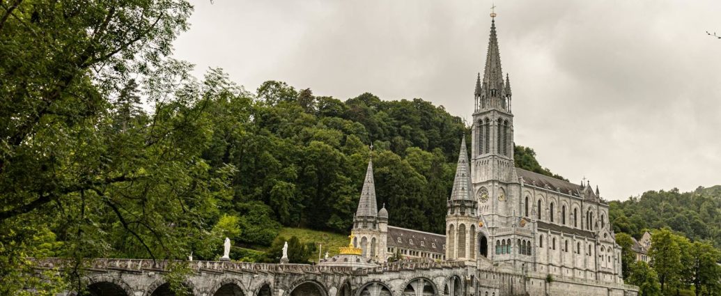 Stunning view of the Basilica of Our Lady of Lourdes against lush green landscape.
