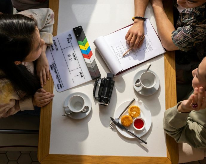 Aerial view of a team discussing a project with a clapperboard in a café setting.